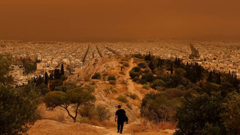 Roter Himmel, rote Erde: Ein Mann wandert am Dienstag in den Hügeln über Athen. (Foto: Reuters)