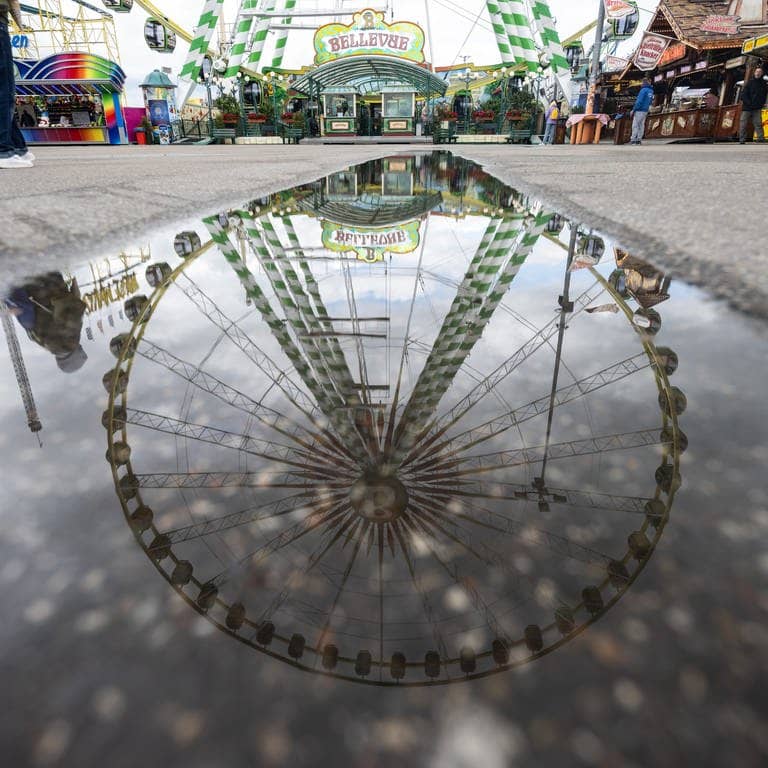 Ein Riesenrad spiegelt sich in einer Pfütze auf dem Festgelände des Stuttgarter Frühlingsfestes. (Foto: dpa Bildfunk, picture alliance/dpa | Marijan Murat)